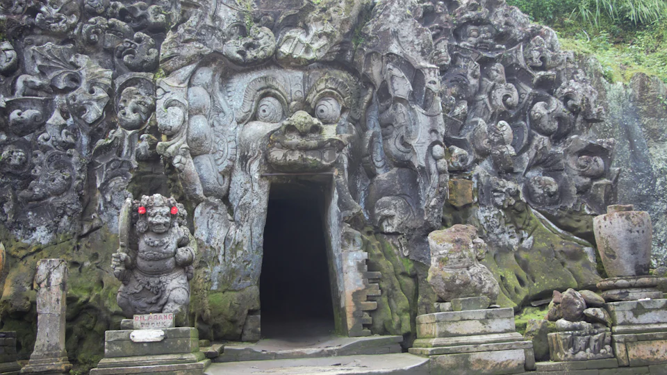 Carved stone gateway of a Balinese temple near Ubud, framed by tropical greenery