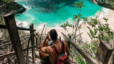 Turquoise bay and limestone cliffs at Kelingking Beach viewpoint on Nusa Penida, with a wooden staircase descending to the sand