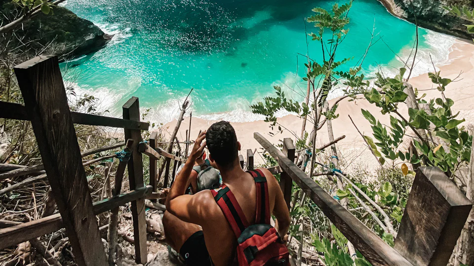 Wooden stairs down a cliff to a turquoise cove on Nusa Penida, Bali