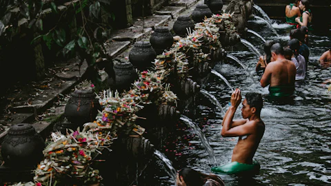 Spring-fed purification pool with carved stone water spouts at a Balinese water temple near Ubud
