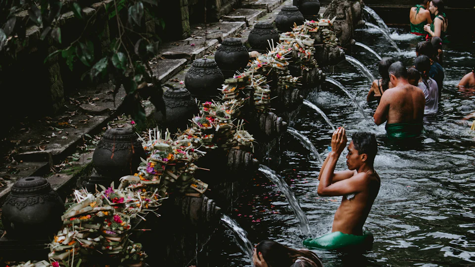 Spring-fed purification pool with carved stone water spouts at a Balinese water temple near Ubud